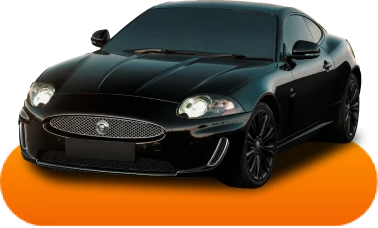 Sleek black sports car with shiny finish, prominent grille, and glowing headlights, parked on an orange surface, conveying luxury and elegance.