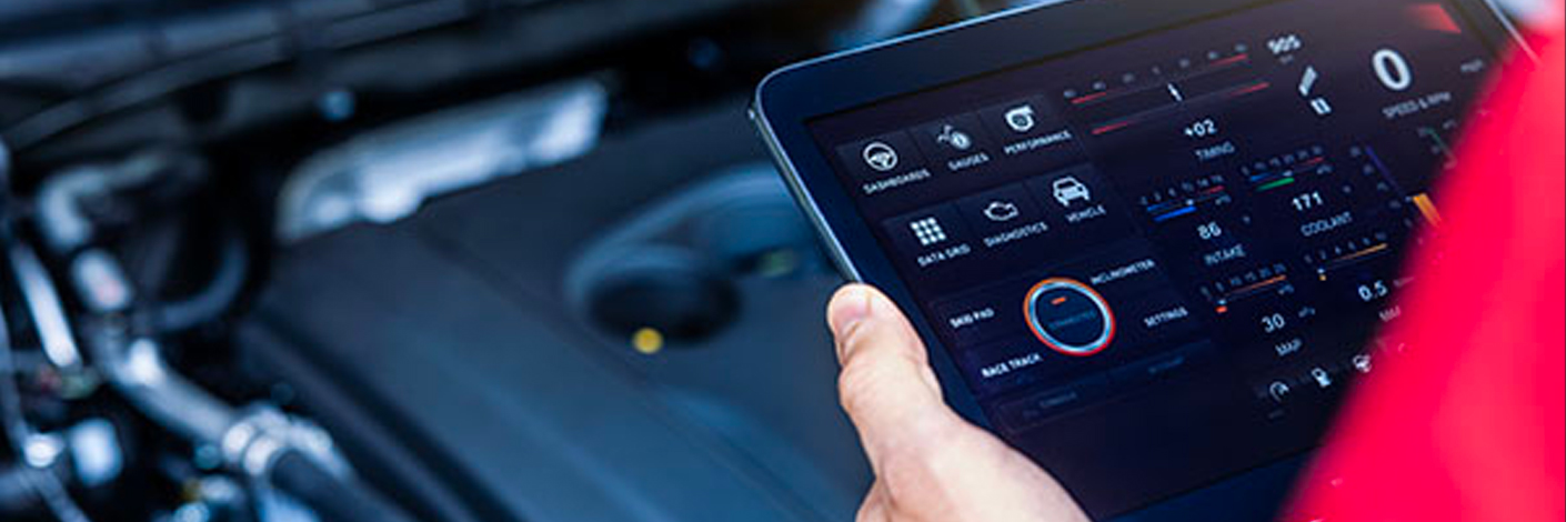 pre-purchase inspection specialist, auto repair in North Bethesda, MD. A person in a red shirt holds a tablet displaying a car diagnostics interface with various readings and icons in front of a car engine.