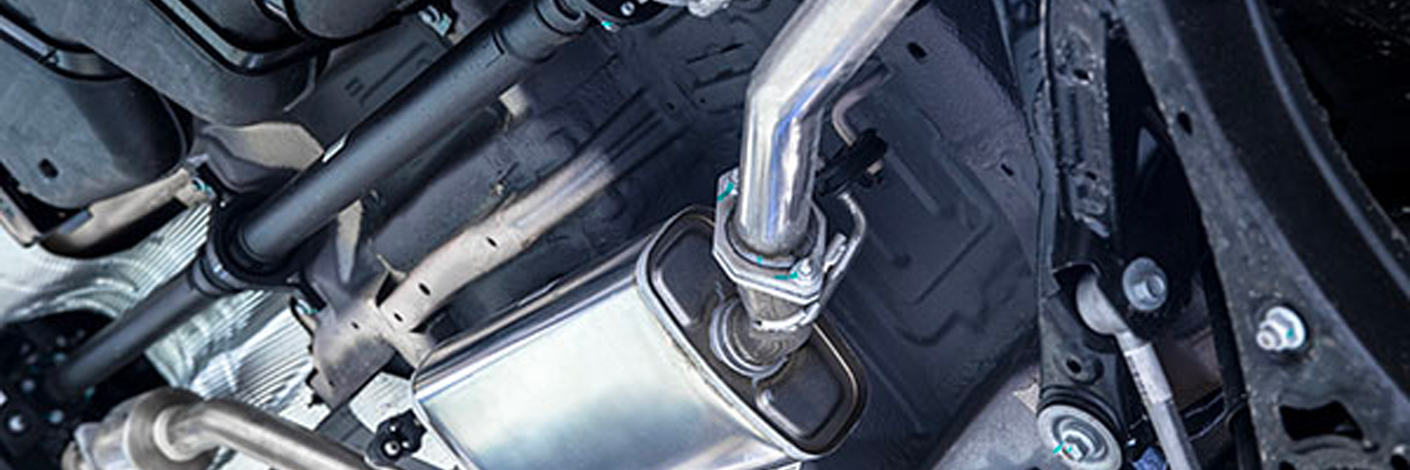 Close-up view of a vehicle's undercarriage, showcasing parts of the exhaust system including pipes and a muffler.