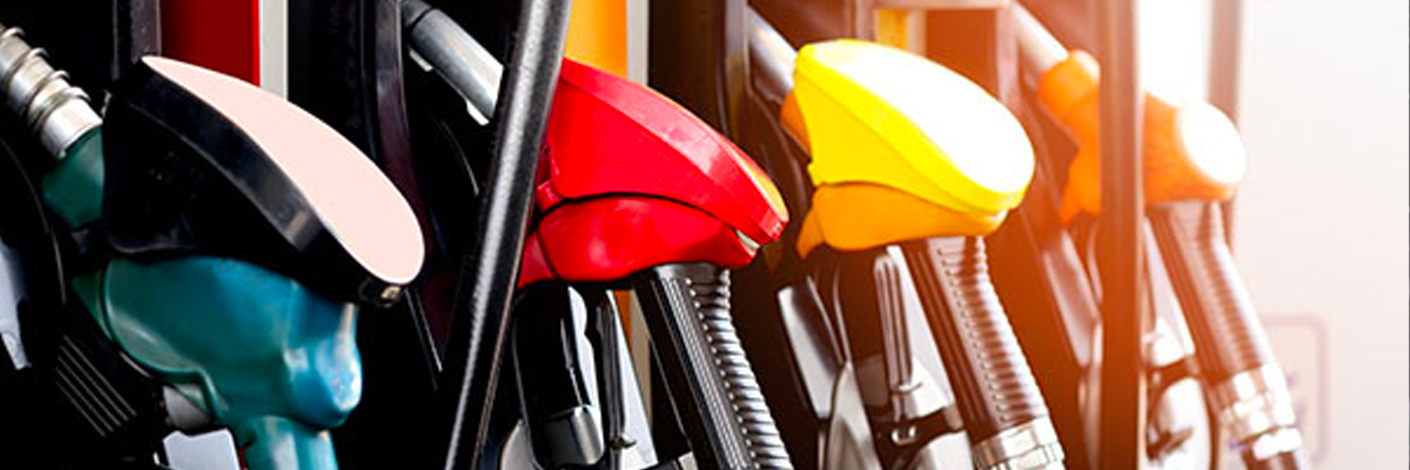 fuel efficiency, auto repair in North Bethesda, MD at MB Automotive Services. A row of fuel pump handles in various colors, including black, red, yellow, and green, are shown at a gas station. The handles are neatly arranged, each with a nozzle attached, ready for fueling vehicles.