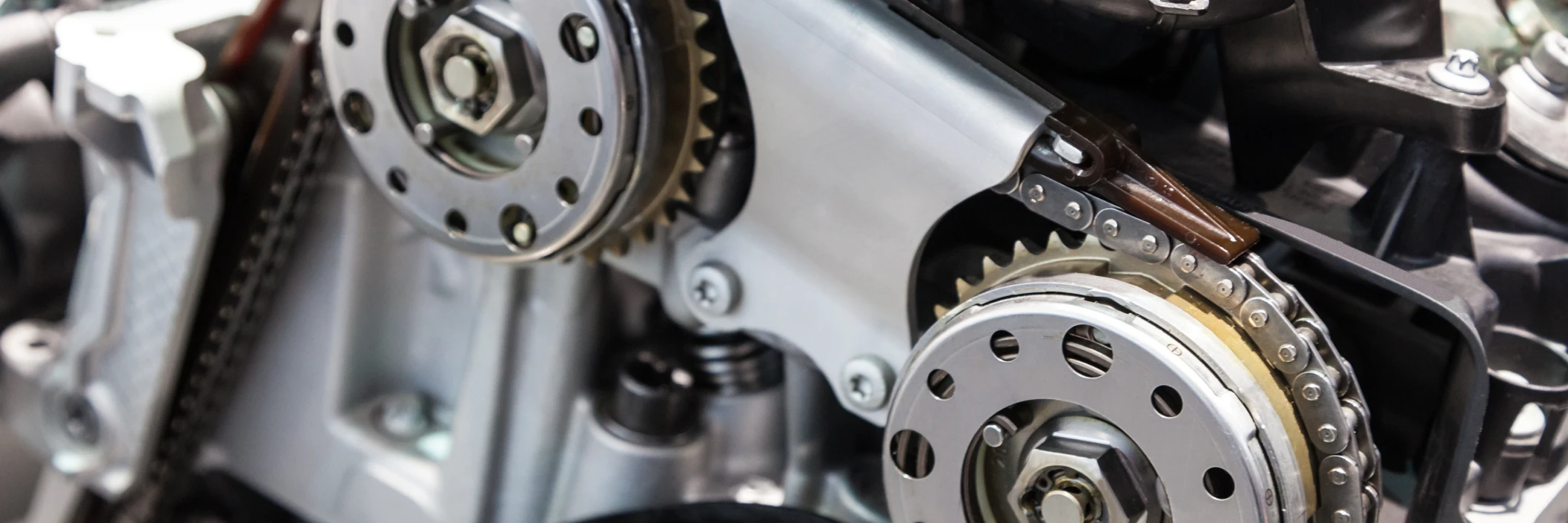 Close-up of a car engine's intricate gears and chains, showcasing polished metal parts and mechanical complexity, conveying precision engineering.