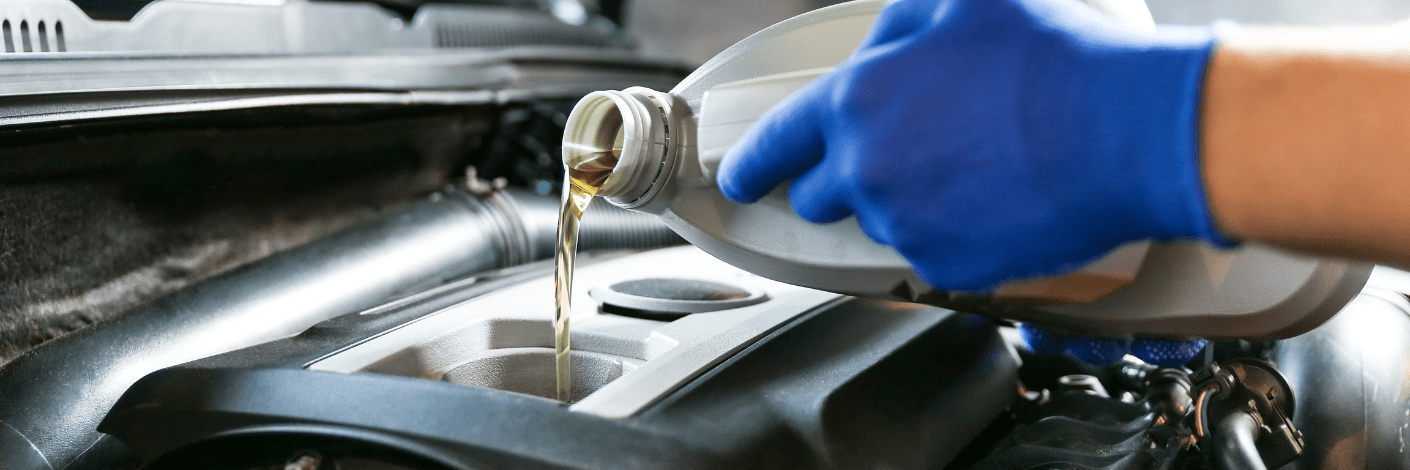 Why Regular Oil Changes Are Critical for Your European Car’s Health. Mechanic with blue gloves pouring engine oil into a car, capturing the importance of routine oil maintenance.