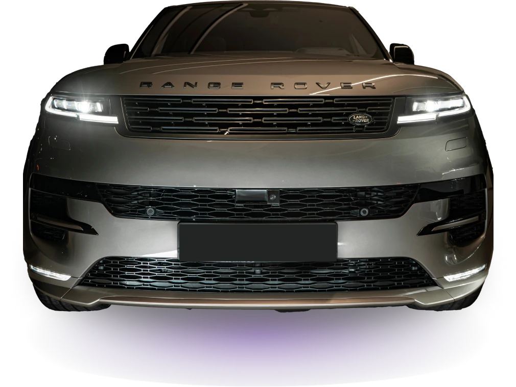 Front view of a silver Range Rover against a dark background. Headlights are on, highlighting the sleek grille and bold, modern design. Elegant and powerful.
